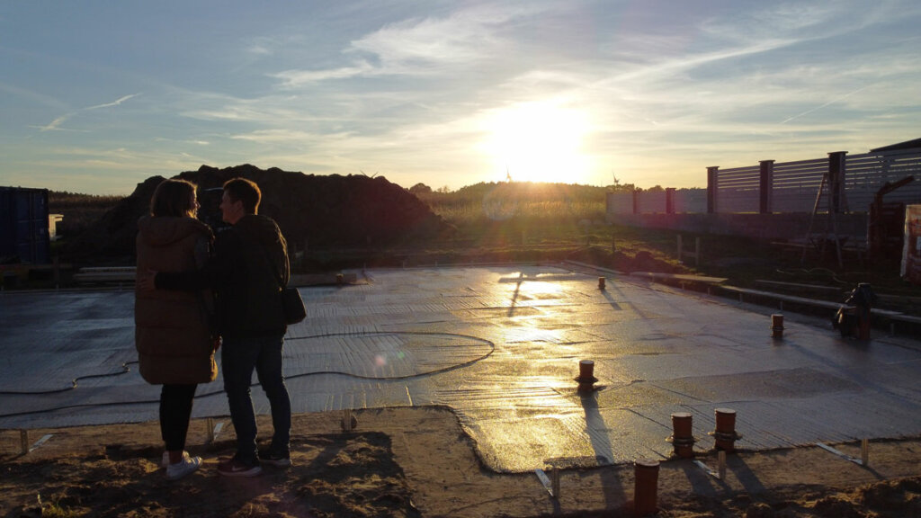 Bauherren schließen in der Abendsonne die Fertigstellung der Beton-Sauberkeitsschicht ab.